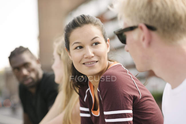 Row of four male and female friends chatting in city skatepark — Stock Photo