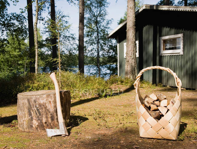 Сокира і дрова біля дерев'яної кабіни — стокове фото