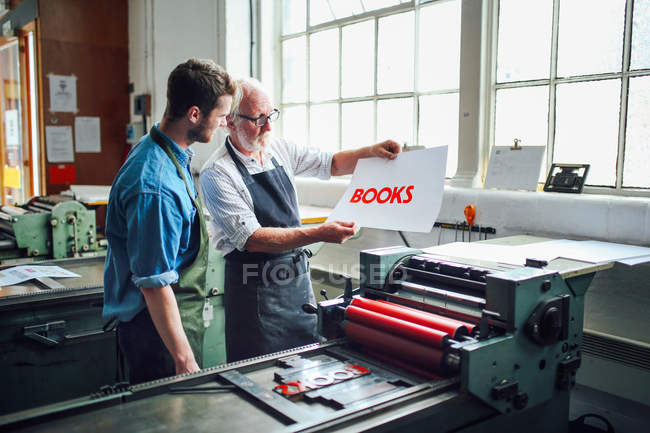Ancien artisan / technicien montrant un jeune homme imprimé à la typographie dans un atelier d'arts du livre — Photo de stock