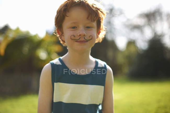 Portrait of young boy with drawn on moustache — Stock Photo