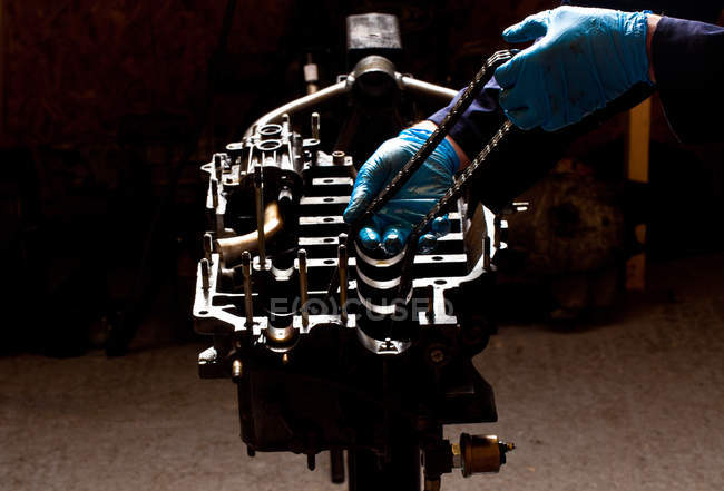 Male mechanic repairing car engine, holding cam chain, cropped shot — Stock Photo