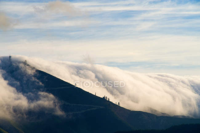 Clouds pouring over rural hillside — Stock Photo