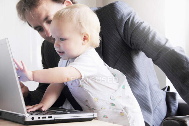 Батько і малюк грають з ноутбуком — стокове фото