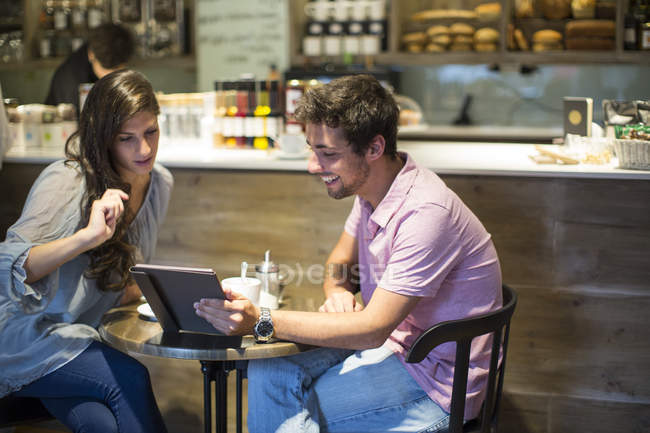 Jeune couple dans un café en regardant tablette numérique — Photo de stock