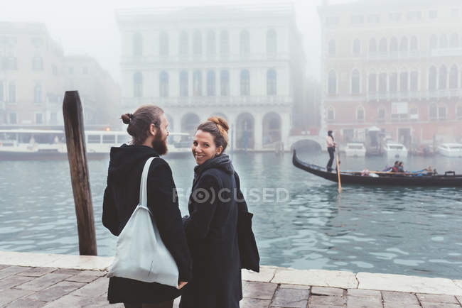 Rear view of couple on misty canal waterfront, Venice, Italy — Stock Photo
