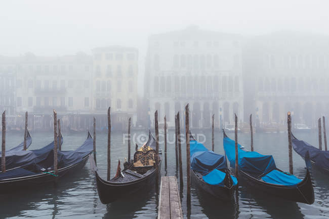 Rows of gondolas moored on misty canal, Venice, Italy — Stock Photo