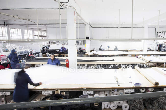 Trabalhadoras da fábrica que desenrolam têxteis na fábrica de vestuário — Fotografia de Stock