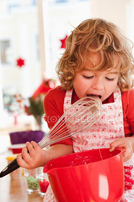 Giovane ragazzo leccare pasta da battitore — Foto stock