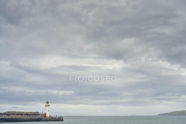 Paisaje marino con pared del puerto y faro, Cumbria, Reino Unido - foto de stock