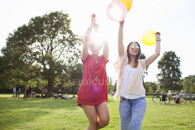 Две девушки танцуют с воздушными шарами на вечеринке в парке — стоковое фото