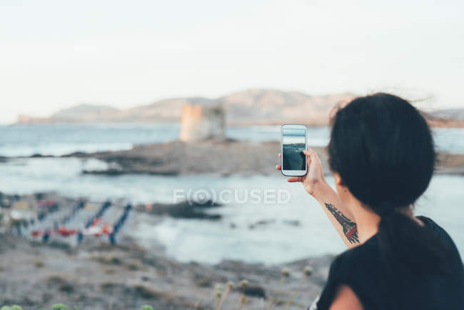 Vue arrière de la femme utilisant un smartphone pour photographier la plage, Stintino, Sassari, Italie — Photo de stock