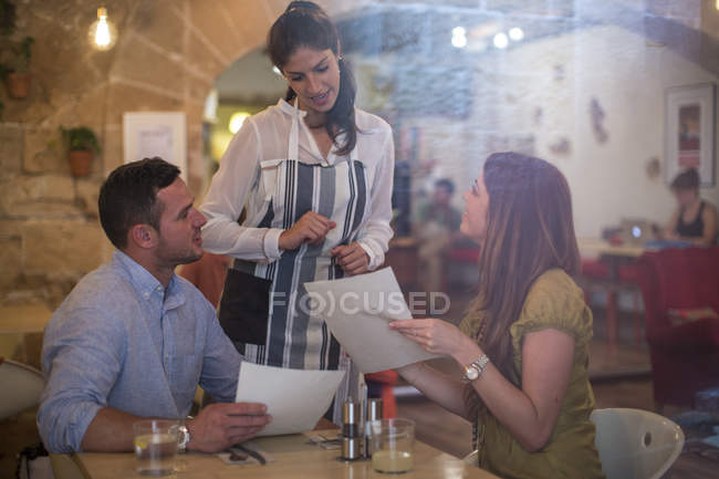 Garçonete servindo clientes em restaurante moderno — Fotografia de Stock