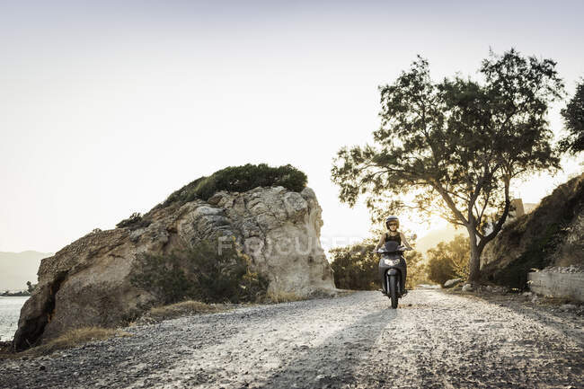 Woman riding moped along coast at Pythagorio, Samos, Greece — Stock Photo