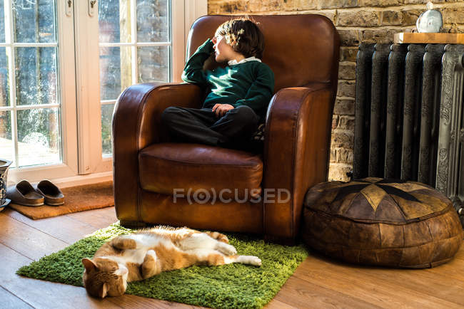 Boy relaxing on arm chair after school — Stock Photo