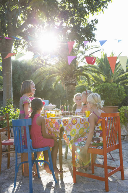 Girls sitting at table with birthday party food — Stock Photo