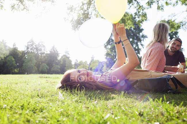 Ritratto di giovane donna sdraiata sull'erba con palloncino alla festa del parco — Foto stock