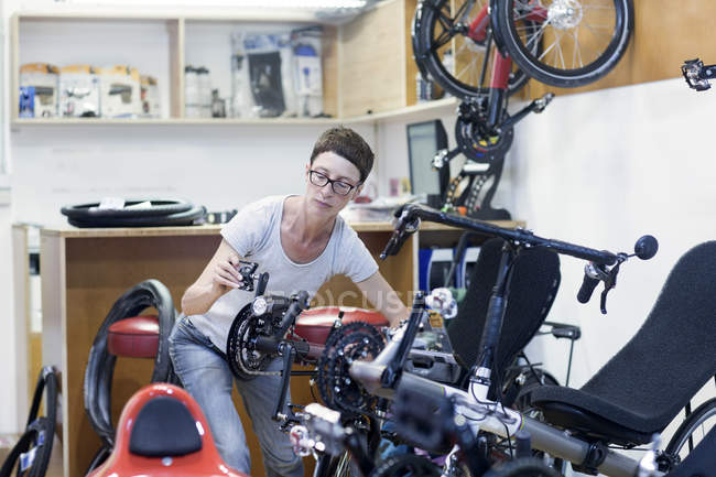 Жінка в майстерню з ремонту велосипедів перевірка педалі на лежачому велосипеді — стокове фото