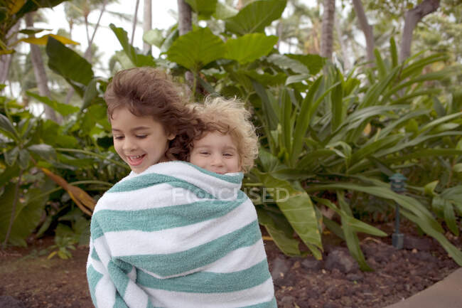 Niño y niña envueltos en toalla - foto de stock
