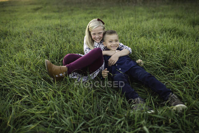Hermano y hermana acostados juntos en la hierba - foto de stock