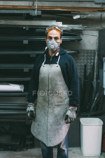 Портрет металлиста в пыльной маске в кузнице — стоковое фото