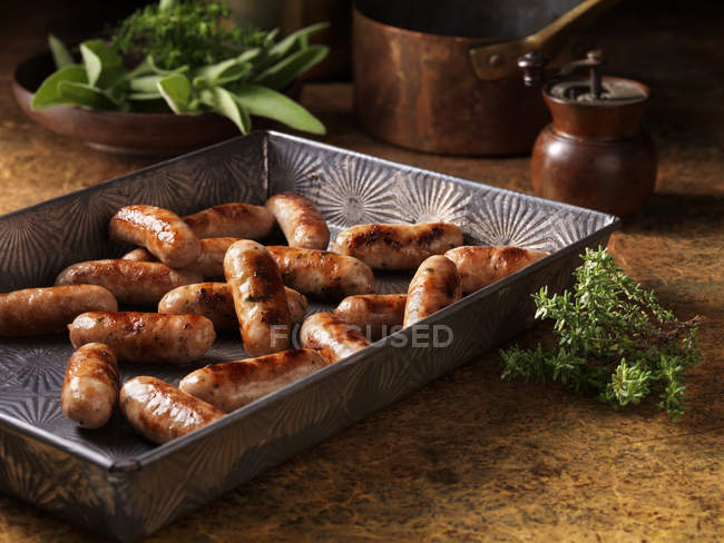 Cocktail sausages in baking tray with herbs — Stock Photo