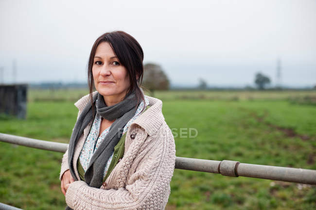 Mujer apoyada en la cerca de la granja - foto de stock