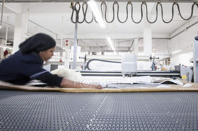Trabajadora de fábrica preparando textiles para maquinaria en fábrica de ropa - foto de stock