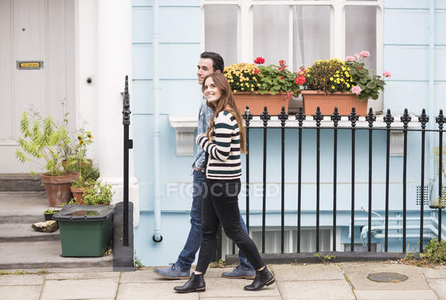 Vista lateral de pareja caminando por la calle sonriendo - foto de stock