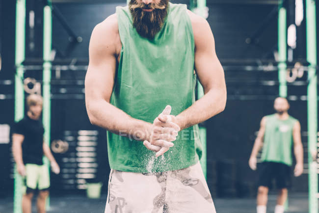 Mid section of male cross trainer chalking hands in gym — Stock Photo