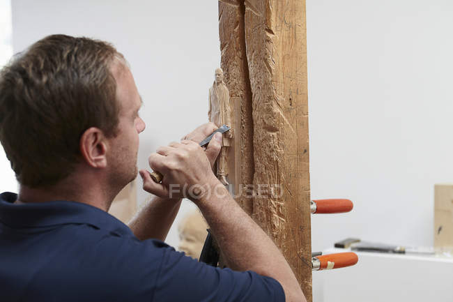 Worker chiseling figure from wood — Stock Photo