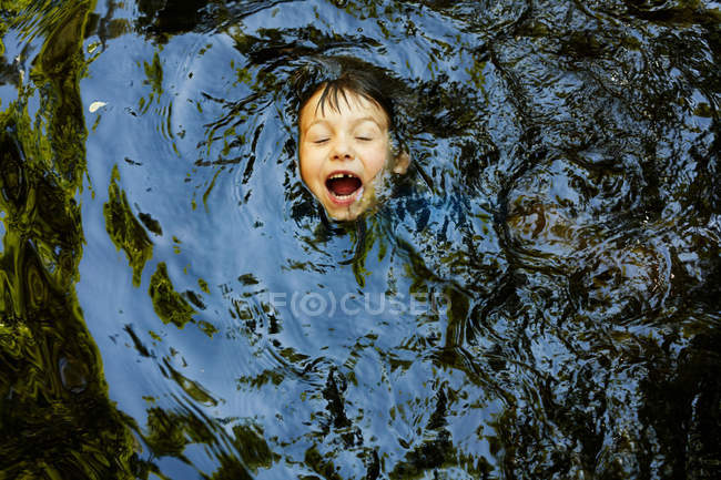 Laughing boy swimming in river — Stock Photo