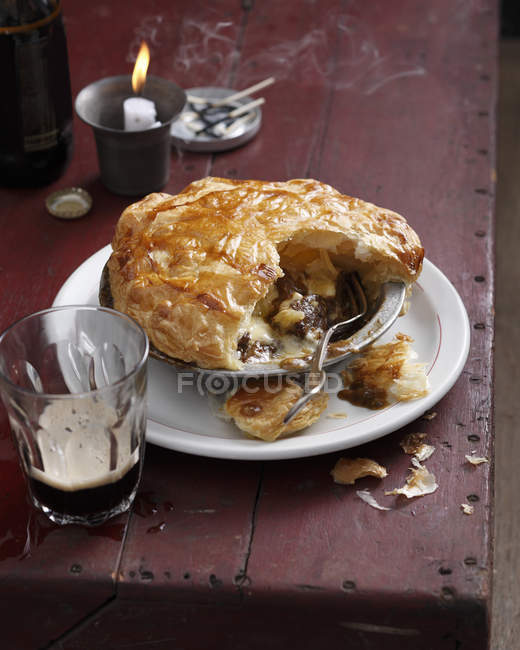 Свіжий приготований м'ясний пиріг, пивний келих і свічка на столі — стокове фото