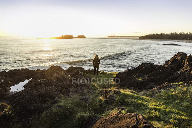 Femme observant le coucher du soleil depuis la côte, parc national Pacific Rim, île de Vancouver, Colombie-Britannique, Canada — Photo de stock