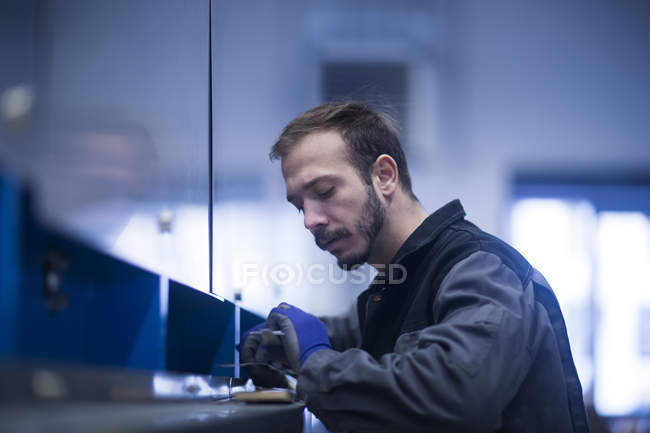 Young adult male Engineer inspecting heavy machinery — Stock Photo