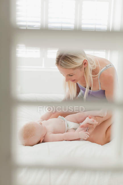 Madre che gioca con il bambino sul letto — Foto stock