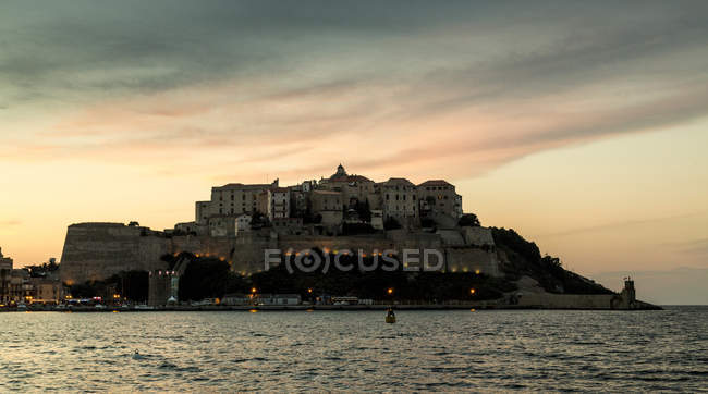 Silhouetted view of sea and Calvi on headland at dusk, Corsica, France — Stock Photo