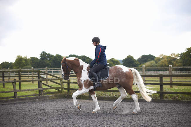 Giovane donna a cavallo intorno paddock — Foto stock