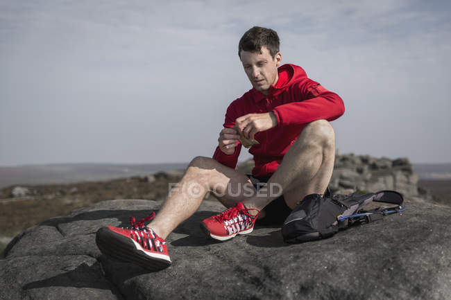 Male runner opening snacks on top of Stanage Edge, Peak District, Derbyshire, UK — Stock Photo