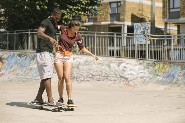 Молодой человек и женщина занимаются скейтбордингом в скейтпарке — стоковое фото
