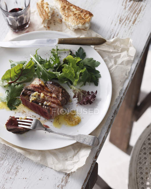 Порция филе миньон со смешанным салатом и столовыми приборами — стоковое фото