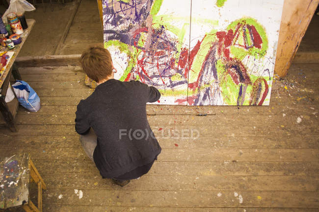 Молодой человек рисует на холсте в студии — стоковое фото