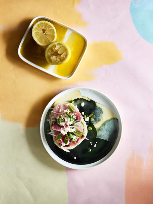 Легкая закуска и тарелка с лимонными половинками на столе — стоковое фото