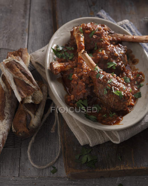 Schüssel mit gekochten Lammhaxen mit Tomatensauce und Kräutern — Stockfoto