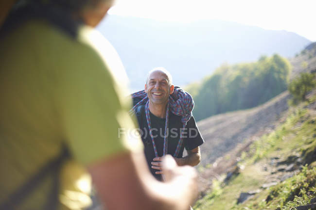 Scalatore di roccia che porta corda sulle spalle sorridendo — Foto stock