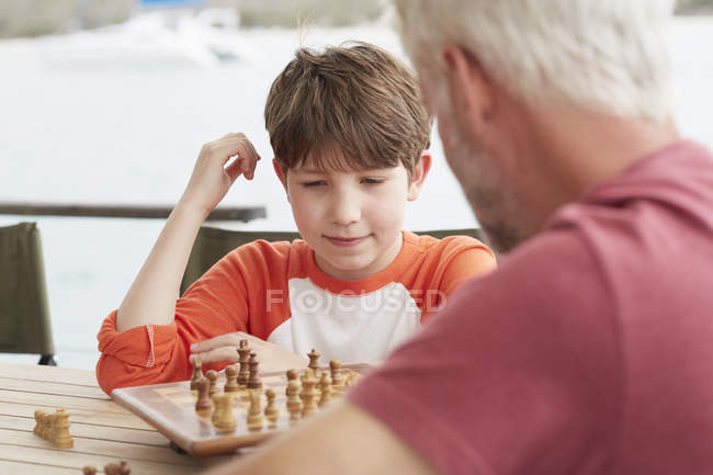 Дедушка и внук вместе играют в шахматы. — стоковое фото