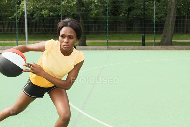 Mulher jogando basquete na quadra — Fotografia de Stock