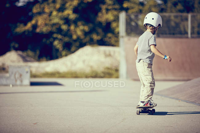 Petit garçon en casque skateboard dans le parc — Photo de stock