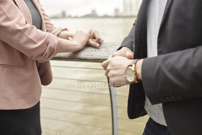 Mid section of businesswoman and businessman meeting on waterfront, London, UK — Stock Photo