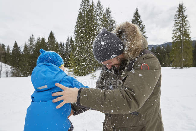Jeune homme et son fils se battent en boule de neige en hiver, Elmau, Bavière, Allemagne — Photo de stock
