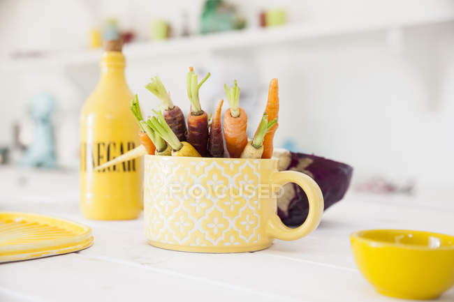 Copa de zanahorias frescas y coloridas en la mesa de la cocina - foto de stock